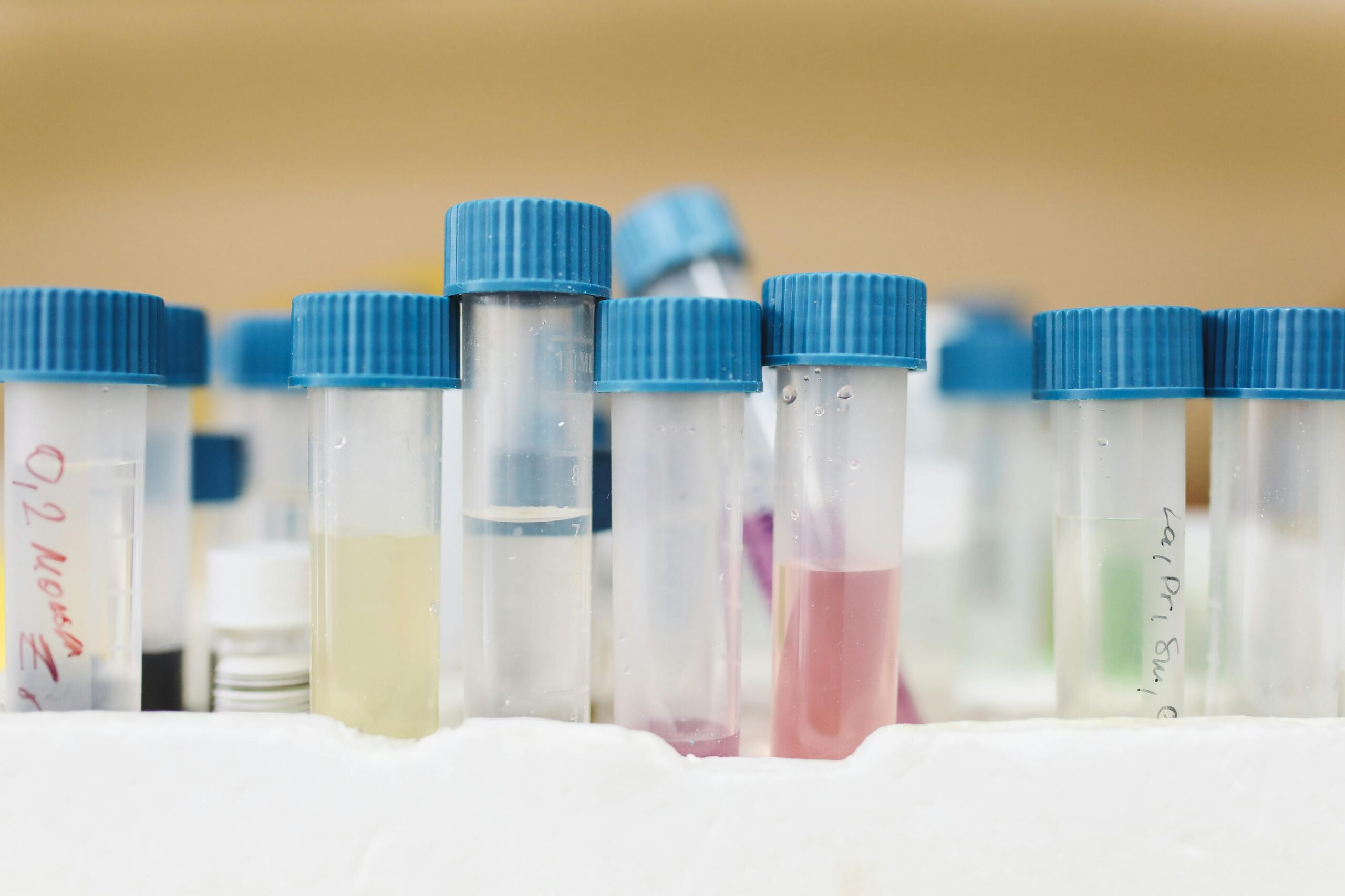 Close-up of colorful test tubes with blue caps in a laboratory setting.