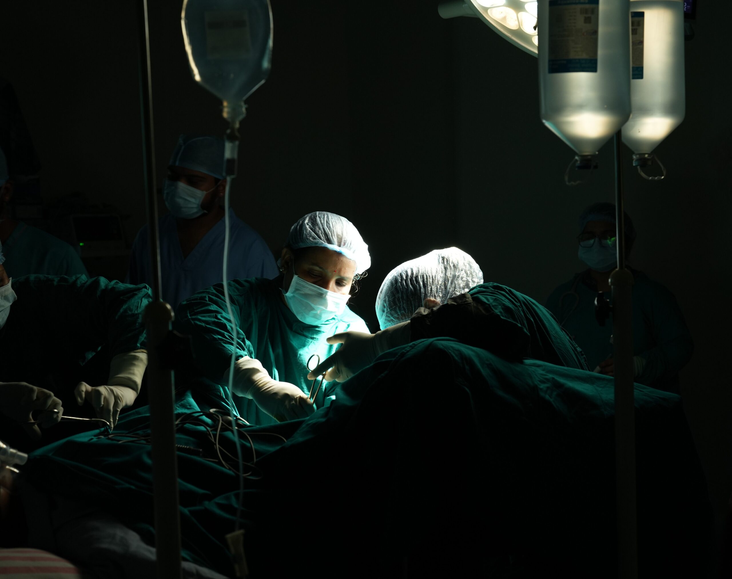 Medical team focused on a critical surgical operation under dim lighting in a hospital.